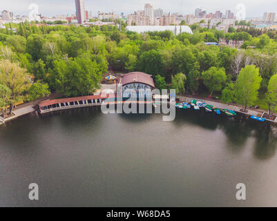 Vista aerea della foresta e lago blu con nuvole di riflessione in Finlandia. Sauna casa al lago. Il molo di legno con barche da pesca. Foto Stock