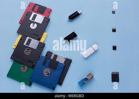 L'evoluzione dei dati digitali del dispositivo di storage. I dischi floppy, unità flash e piccole schede di memoria. Isolato su uno sfondo blu. Foto Stock