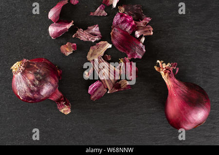Gruppo di due intero lotto di pezzi di stantio cipolla rossa flatlay sulla pietra grigia Foto Stock