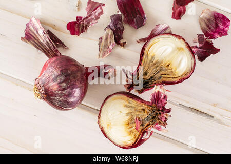 Gruppo di una intera due metà partita di pezzi di stantio cipolla rossa flatlay su legno bianco Foto Stock