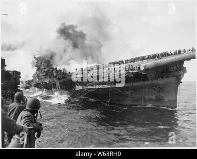 USS SANTA FE pone al fianco di USS FRANKLIN assistenza rendering dopo il vettore era stato colpito e mise in fiamme da un giapponese dive bomber.; Note Generali: Utilizzo di guerra e di conflitto numero 979 quando si ordina una riproduzione o la richiesta di informazioni su questa immagine. Foto Stock