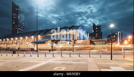 Lunga esposizione di notte del tram che passa in Lower Mosley Street con Manchester Central e Beetham Tower sullo sfondo Foto Stock