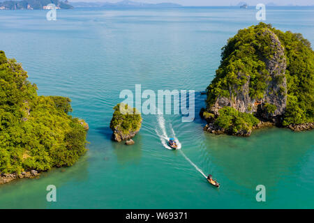 Antenna fuco vista delle barche longtail passando tra 2 piccole, rocky isole tropicali Foto Stock