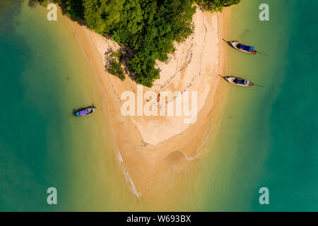 Top down vista aerea delle tradizionali barche longtail ormeggiato a una bella, tropicali piccola spiaggia sabbiosa Foto Stock