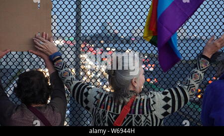 I manifestanti tenendo le mani sul Berkeley ponte pedonale oltre l'autostrada 80 con bandiera arcobaleno. Luci per la veglia di Liberty per protestare contro di noi i campi di detenzione. Foto Stock