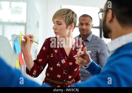 Ritratto di una bionda di capelli corti donna a capo di un team diversificato di creative millenaria i colleghi in un avvio di strategie di brainstorming Foto Stock