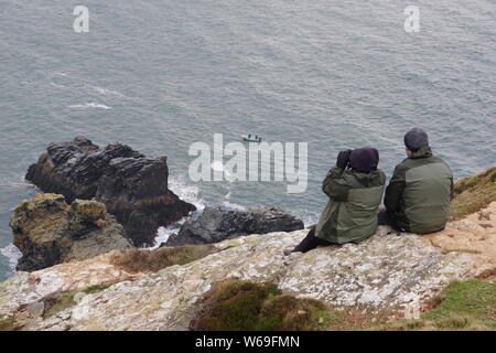 Whale Watching seduto su St Agnes testa in cima alla scogliera. North Cornish Coast, UK. Molla, 2019. Foto Stock