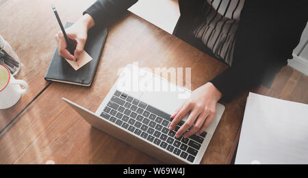 Vista superiore del giovane designer modifica i suoi progetti con penna stilo in un rilassante ambiente di lavoro Foto Stock