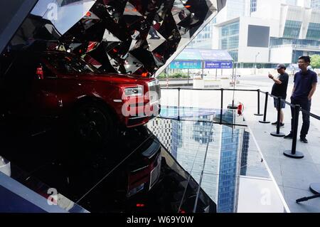 Pedoni di scattare delle foto di un SUV Cullinan di Rolls-Royce sul visualizzatore in corrispondenza di un centro commerciale per lo shopping nella città di Hangzhou, a est della Cina di provincia dello Zhejiang, 19 giugno 2018. Foto Stock