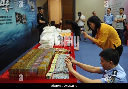 Un Cinese funzionario di polizia e di un giornalista di scattare foto delle droghe sequestrate dalla polizia di Guangdong sul display durante una conferenza stampa nella città di Guangzhou, sout Foto Stock