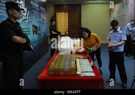 Un Cinese funzionario di polizia e di un giornalista guardare droghe sequestrate dalla polizia di Guangdong sul display durante una conferenza stampa nella città di Guangzhou, Cina del Sud Foto Stock