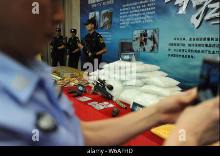 Un Cinese funzionario di polizia prende le foto delle droghe sequestrate dalla polizia di Guangdong sul display durante una conferenza stampa nella città di Guangzhou, a sud della Cina di Guangd Foto Stock