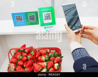 --FILE--un cliente usa il suo smartphone per eseguire la scansione del codice QR di WeChat pagamento dell'applicazione Messaggistica Weixin o WeChat, di Tencent per pagare strawberrie Foto Stock