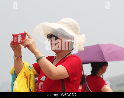 I turisti stranieri proteggersi con cappelli ombrello dal sole cocente alla Piazza Tian'anmen a Pechino in Cina, 26 giugno 2018. Molte città Foto Stock