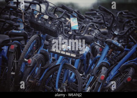 Le biciclette cinesi di bike sharing service Bluegogo sono impilati in un abbandonata fabbrica di mattoni in città Wangzuo, Fengtai District, Pechino, Cina, 6 giugno Foto Stock