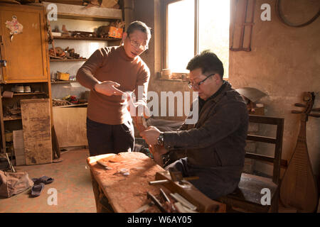 --FILE--artigiano cinese Li Zhaolin incarica un visitatore per rendere la pipa, a quattro corde cinese strumento musicale, nel suo studio di Suzhou City, est Foto Stock