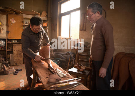 --FILE--artigiano cinese Li Zhaolin incarica un visitatore per rendere la pipa, a quattro corde cinese strumento musicale, nel suo studio di Suzhou City, est Foto Stock