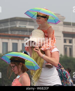 I turisti stranieri proteggersi con cappelli ombrello dal sole cocente alla Piazza Tian'anmen a Pechino in Cina, 26 giugno 2018. Molte città Foto Stock