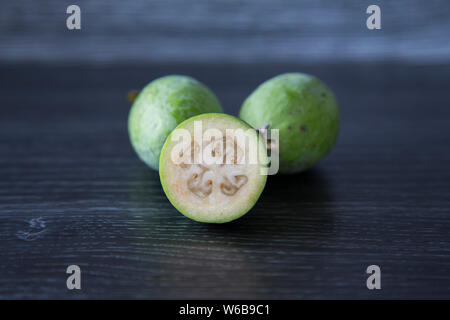 Homegrown feijoas organico. Tutta la frutta e tagliate la frutta. Ruvida di pelle verde con il grintoso carne pallido e gelatina come interno con semi. Poter tagliare a metà Foto Stock