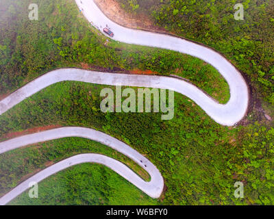 Auto Drive su un tratto di strada tortuosa con curve 45 che collega Xiushan Tujia e Miao contea autonoma e Chuanhegai punto panoramico circondato da nebbia in Foto Stock