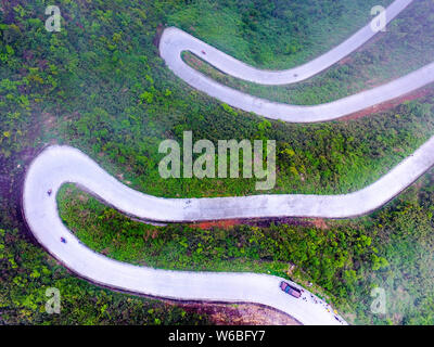 Auto Drive su un tratto di strada tortuosa con curve 45 che collega Xiushan Tujia e Miao contea autonoma e Chuanhegai punto panoramico circondato da nebbia in Foto Stock