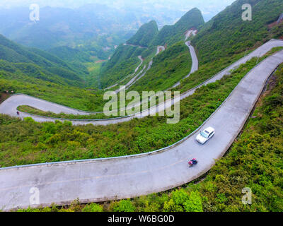 Auto Drive su un tratto di strada tortuosa con curve 45 che collega Xiushan Tujia e Miao contea autonoma e Chuanhegai punto panoramico circondato da nebbia in Foto Stock