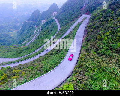 Auto Drive su un tratto di strada tortuosa con curve 45 che collega Xiushan Tujia e Miao contea autonoma e Chuanhegai punto panoramico circondato da nebbia in Foto Stock