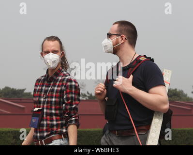 --FILE--i turisti stranieri che indossano maschere viso contro l' inquinamento atmosferico visitare la Piazza Tian'anmen in pesanti smog a Pechino, in Cina, il 2 aprile 2018. Come il Foto Stock