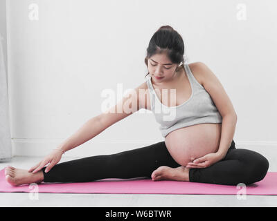 Asian donna incinta fare yoga a casa, il concetto di stile di vita. Foto Stock