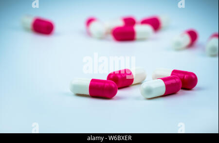 Rosa-bianco pillola della capsula sulla capsula sfocata sullo sfondo. Farmaco antibiotico resistenza. Capsula di antimicrobici pillole. Farmacia farmacia. Prodotti farmaceutici Foto Stock