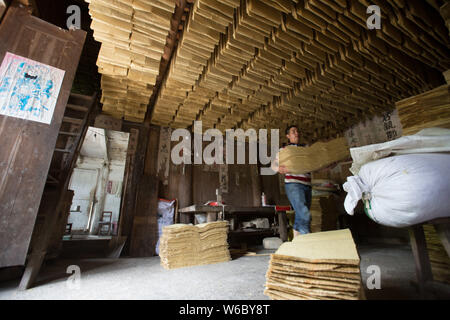 Artigiano cinese Hu Zongliang rende joss carta fatta di fibra di bambù in modo tradizionale presso la sua bottega in borgo Xiangzhigou, Wudang distretto, Guiya Foto Stock