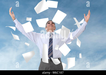 Carte che cadono su un uomo d'affari in piedi con le braccia distese Foto Stock