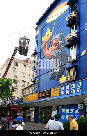 Una donna artista argentino crea un muro dipinto a tema la cura dei bambini e degli animali su un edificio residenziale sulla strada lamellatura a Shanghai in Cina Foto Stock