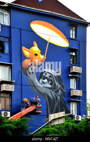 Una donna artista argentino crea un muro dipinto a tema la cura dei bambini e degli animali su un edificio residenziale sulla strada lamellatura a Shanghai in Cina Foto Stock