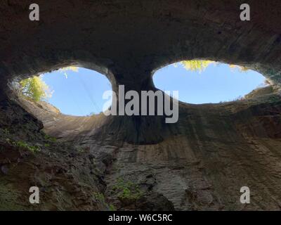 Ripresa da una grotta di due fori in una grotta forma degli occhi Foto Stock