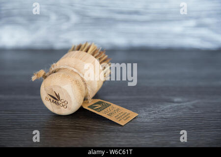 Andare di marca BAMBOO veggie spazzola con fibre di bass, spago tag. Materiali biodegradabili. Seduta in legno scuro grano banco di cucina. Il concetto di sostenibilità. Foto Stock