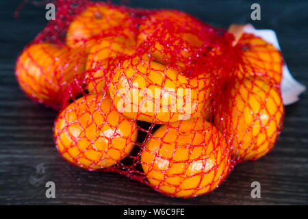 Mandarini in plastica rosso borsa a rete. Comodo e fresco modo di imballaggio di frutta e verdura. Dannoso per l'ambiente e la vita marina. Foto Stock