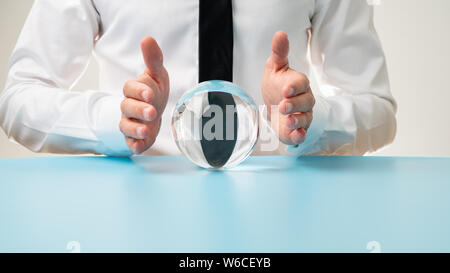 Imprenditore tenendo le mani protettiva su una sfera di cristallo in una immagine concettuale. Foto Stock