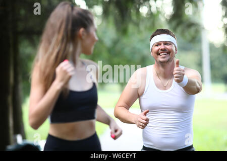 Grassi uomo millenario in esecuzione nel parco con Foto Stock