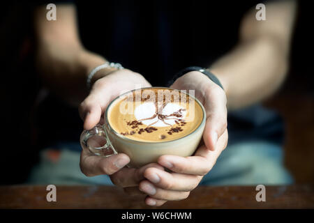 Gli uomini mano che regge una tazza di caffè latte a forma di albero.focus sensibili Foto Stock