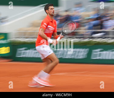 Moto sfocata del tennista serbo Novak Djokovic in esecuzione in avanti durante il French Open 2019, Parigi, Francia Foto Stock