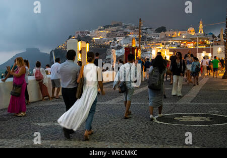 Fira, Grecia - 14 Luglio 2019: turisti passeggiare lungo la scogliera in strada in cima al tramonto su Ipapantis Foto Stock