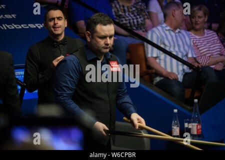 Stephen Maguire della Scozia gioca un colpo a Ronnie O'Sullivan dell'Inghilterra in il loro match di primo turno durante il 2018 Betfred World Snooker Championship Foto Stock