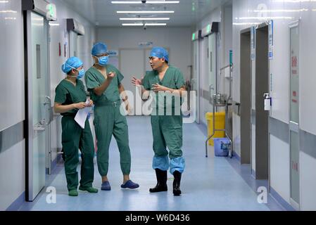 (190801) -- ZHENGZHOU, 1 Agosto, 2019 (Xinhua) -- Feng Xiuling (R) comunica con lo staff medico dopo una chirurgia presso la camera operativa di Henan Malattie infettive ospedale di Zhengzhou, capitale della Cina centrale della Provincia di Henan, 31 luglio 2019. Feng Xiuling, 54, è il primo medico per eseguire interventi chirurgici per i malati di AIDS in Henan. Dal 2002, Feng ha condotto più di tremila ambulatori per pazienti di AIDS, in cui egli è stato a rischio di esposizione a HIV infezione per quattro volte. "Il mio lavoro è come camminare su una lama,' ha detto.Il reparto chirurgico Feng sta lavorando per esegue quasi 800 interventi chirurgici Foto Stock