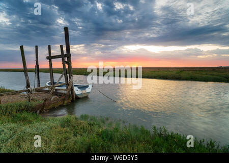Tramonto su una barca ormeggiata in un vecchio pontile in legno a Thornham sulla costa di Norfolk Foto Stock