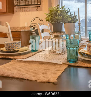 Square sala da pranzo con una vista attraverso la finestra del lago di montagna innevata e cielo molto nuvoloso Foto Stock