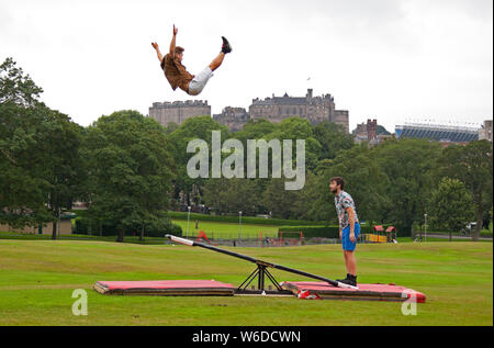 Bruntsfield Links, Edimburgo, Scozia, Regno Unito. Il 1 agosto 2019. Edinburgh Fringe Photocall. Il cast di Super domenica da High Flying Circus finlandese stelle corsa di cavalli azienda utilizzando un teeterboard di lanciare stessi nell'aria sopra il link, con lo splendido skyline di Edimburgo, tra cui il castello, in background. Jarno Polhuij (t-shirt colorate) e Rauli DahlBerg (marrone camicia). Credito: Arch bianco/Alamy Live News Foto Stock