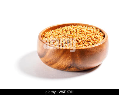 Fenugreek (Trigonella) in una coppa di legno su sfondo bianco Foto Stock