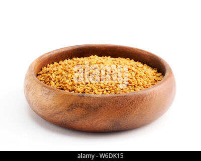 Fenugreek (Trigonella) in una coppa di legno su sfondo bianco Foto Stock