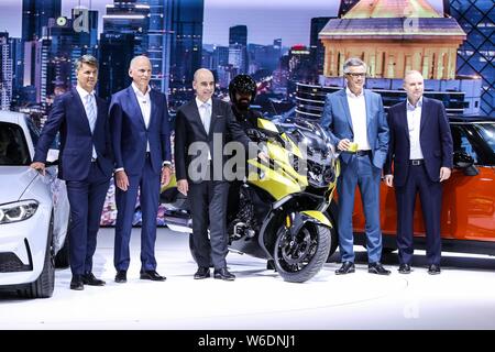 Harald Kruger, sinistra, CEO e presidente del consiglio di amministrazione di BMW AG e altri dirigenti pongono presso lo stand della BMW durante il XV Pechino Inte Foto Stock